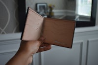 a person holding an open wallet in front of a mirror