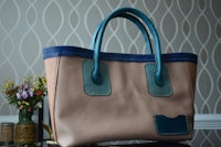 a tan and blue handbag sitting on a table