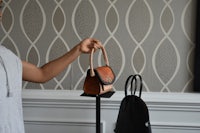 a man is holding a handbag on a stand