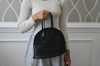 a woman in a plaid skirt holding a black purse